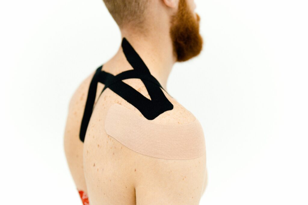 Close-up view of kinesio tape applied to a man's shoulder for medical treatment.